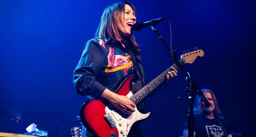 Kim Deal plays her Fender Strat as she performs at London&#039;s Roundhouse in June 2025, the stage lit up in blue.