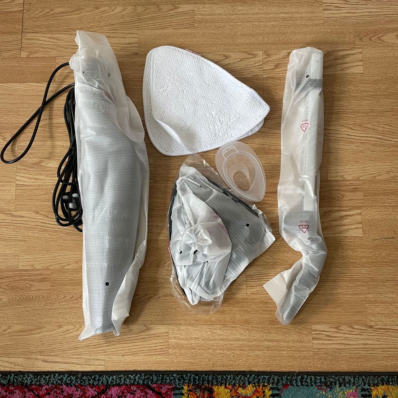 Vileda Steam Mop Plus components wrapped in packaging on wooden laminate floor
