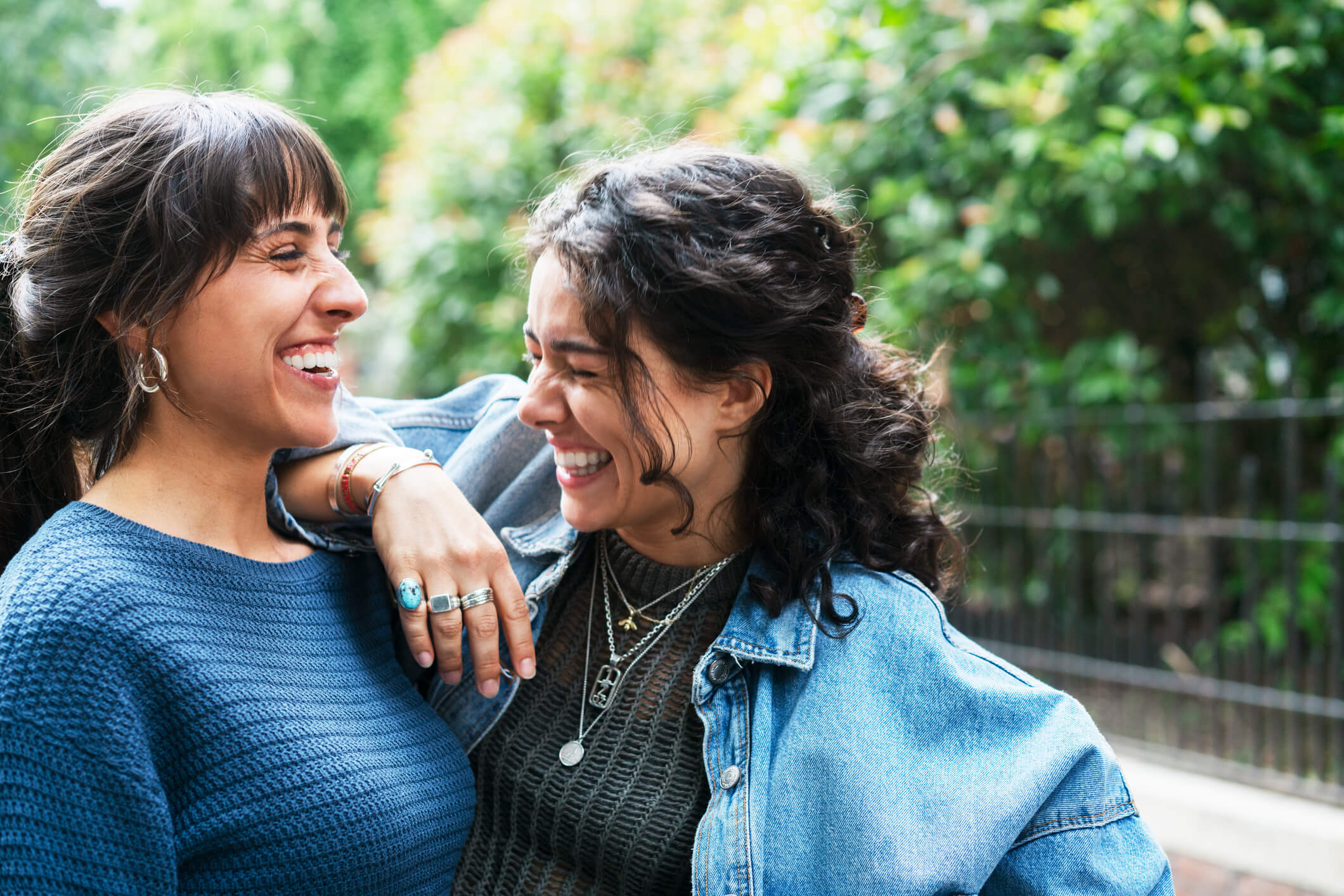Two happy friends giggling together while outdoors.