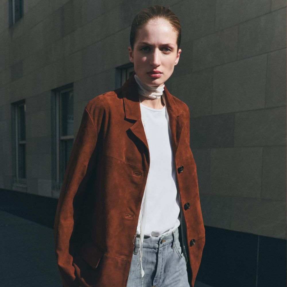 Woman wears suede jacket, white T-shirt, blue jeans 