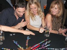 Celebrities playing a game round a table at a party
