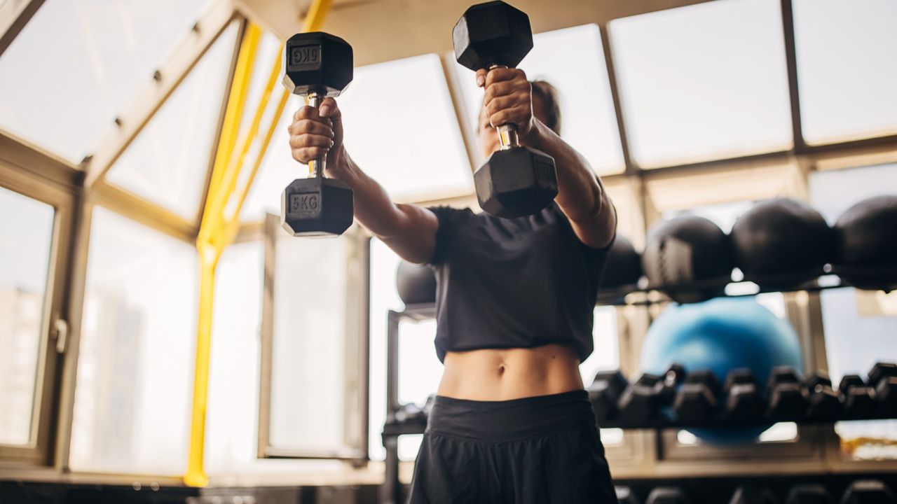 A woman performing dumbbell front raises