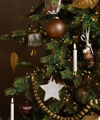 close-up of a christmas tree decorated with clip on candle lights, a vintage picture frame ornament and stars