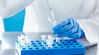 A scientist is shown pipetting a liquid into a test tube in the lab.