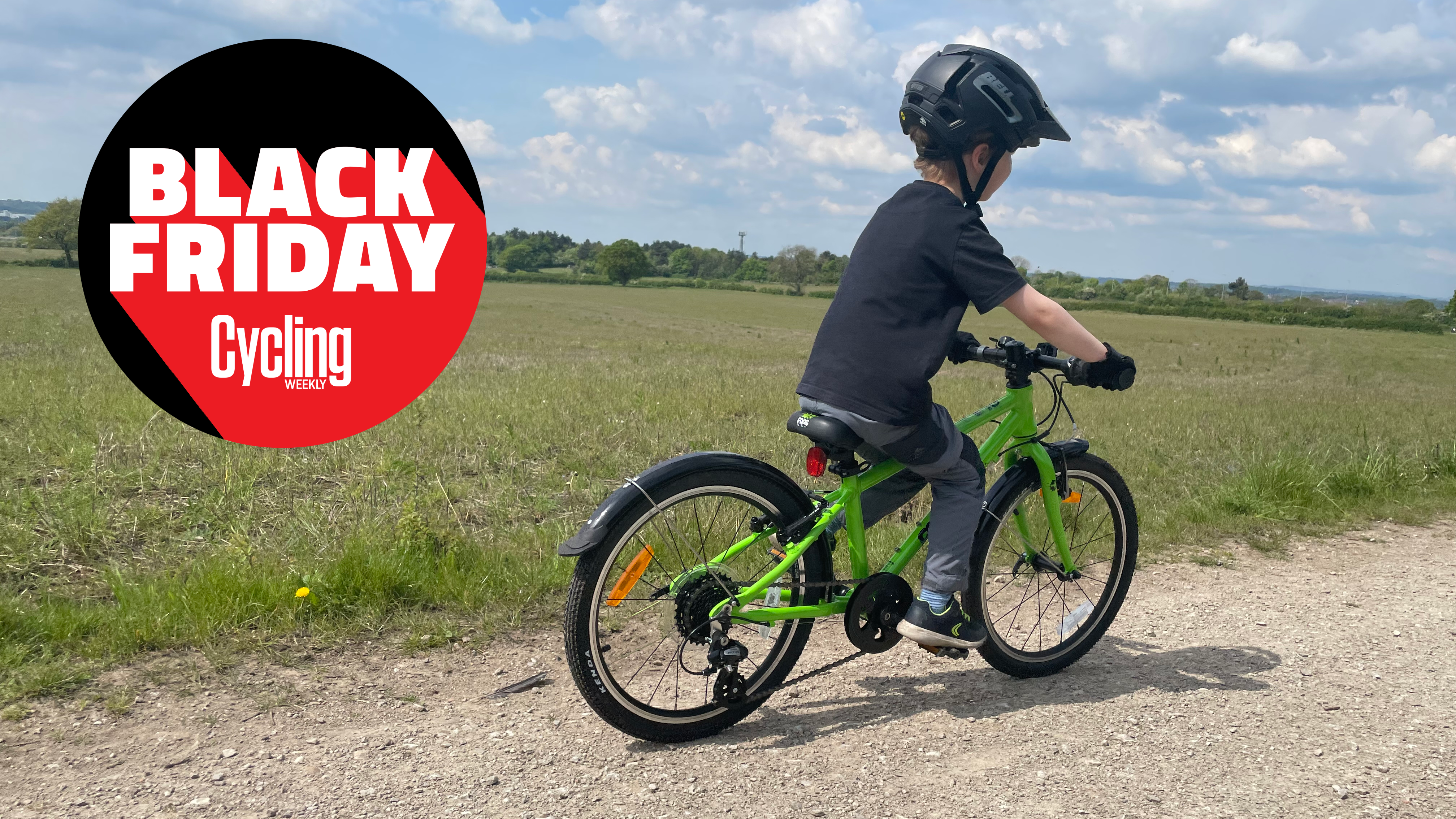 Child riding a green Frog bike across fields