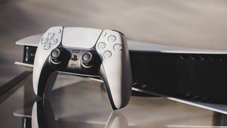 En PlayStation-kontroller står lutad mot ett PlayStation 5 som ligger på ett glasbord.