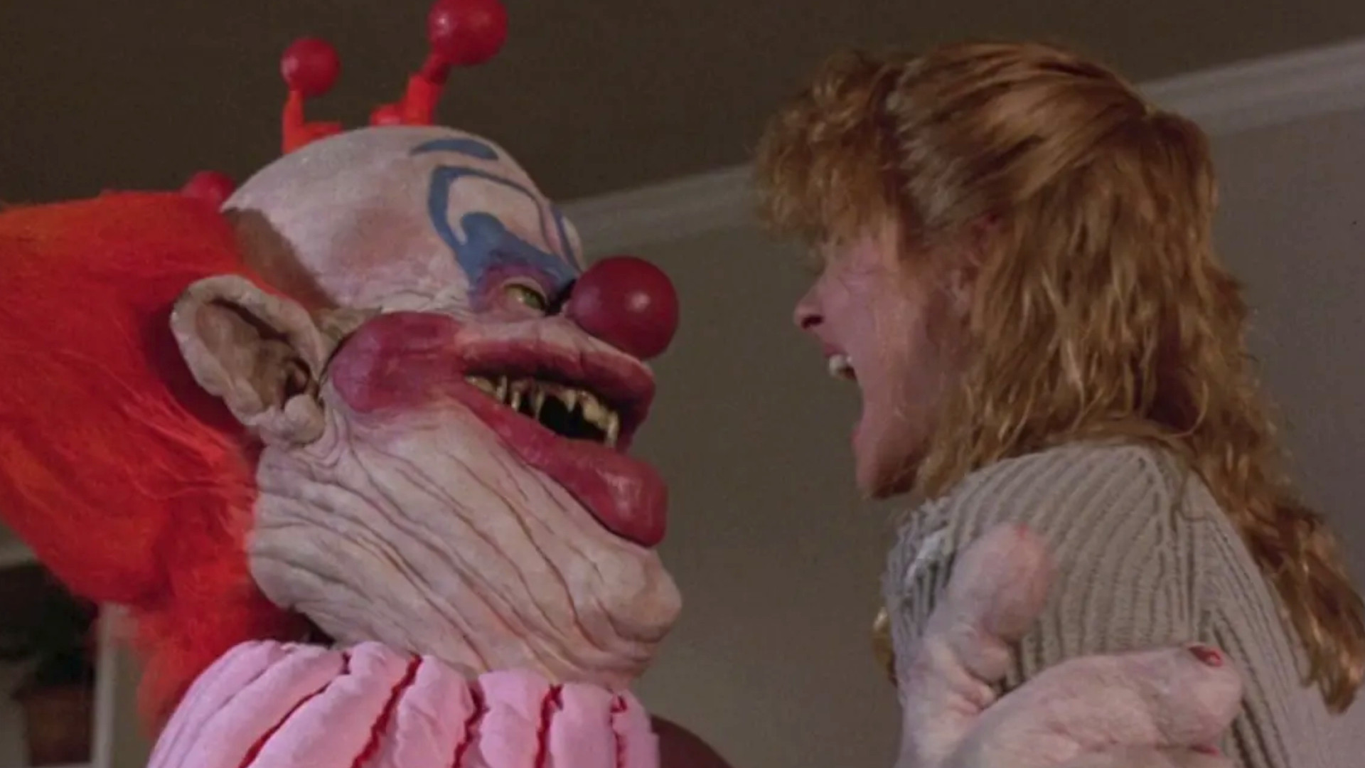 A Killer Klown holding a screaming woman during one of the best scary movies Killer Klowns from Outer Space