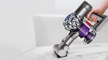 Dyson handheld vacuum cleaning white carpet on stairs