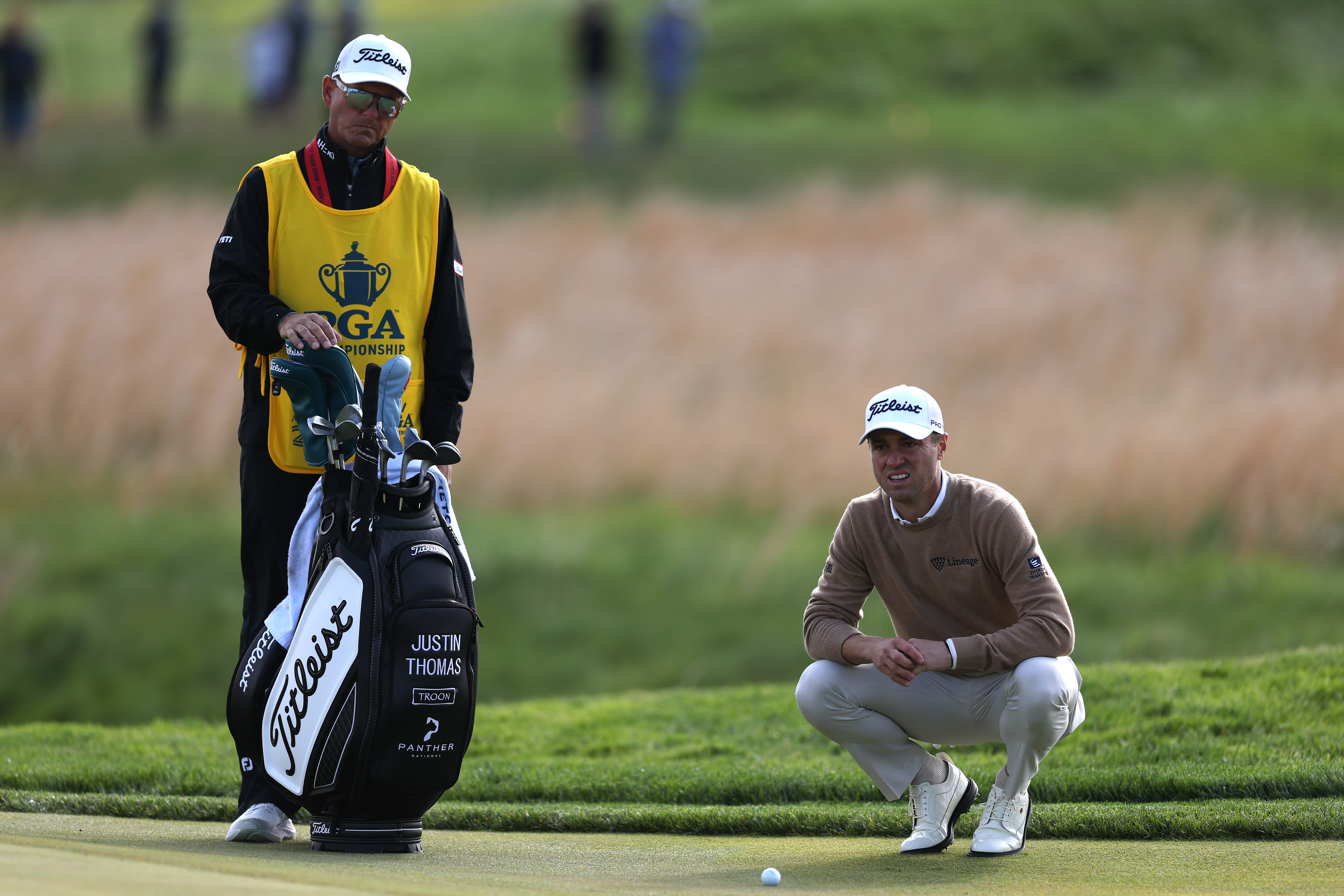 Justin Thomas of the United States lines up a putt with his caddie Matt Minister on the tenth green during the second round of the PGA Championship at Aronimink Golf Club