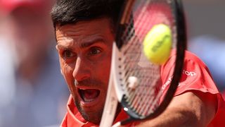 Close-up of Novak Djokovic of Serbia vigorously striking a tennis ball during the 2023 French Open at Roland Garros.