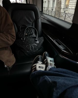 Woman traveling, wearing Adidas Samba shoes in the back of car