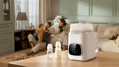 KleanPal Pro Bottle Washer in the foreground with two people having a happy time with their baby in the background