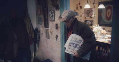 Larry Fink in hat, holding newspaper, film still from FINK, 2024 