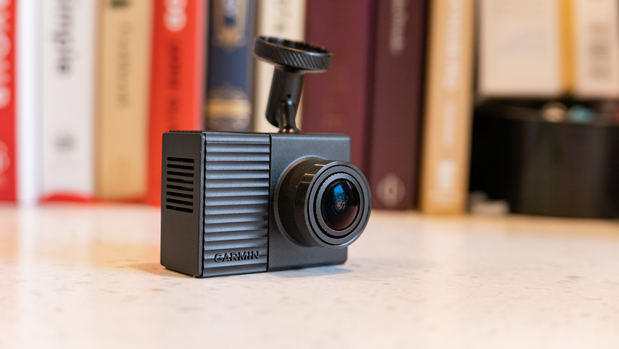 The Garmin Dash Cam Tandem on a table in front of books