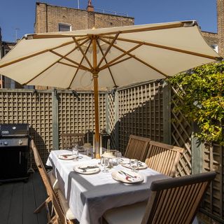 On the terrace of Farnell Mews showing wooden deck and furniture with cream umbrella