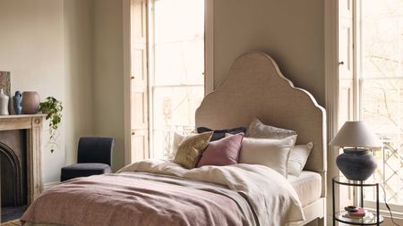 luxurious bed in neutral bedroom with large pink bedroom, pillows and large bedside lamp