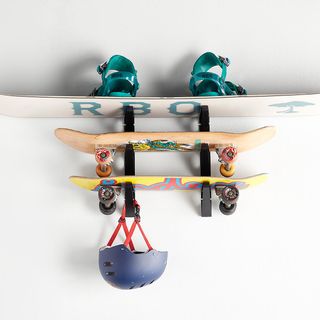a board rack used to store multiple skateboards, a snowboard, and a blue helmet