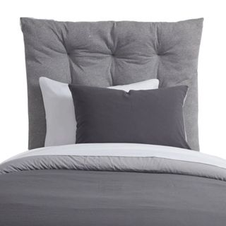A gray headboard with gray and white bedding