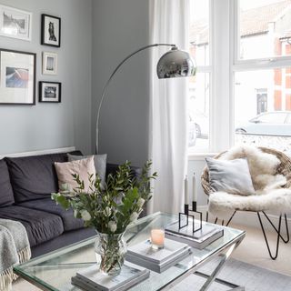 grey living room with grey sofa and chrome arched overhead lamp and glass table