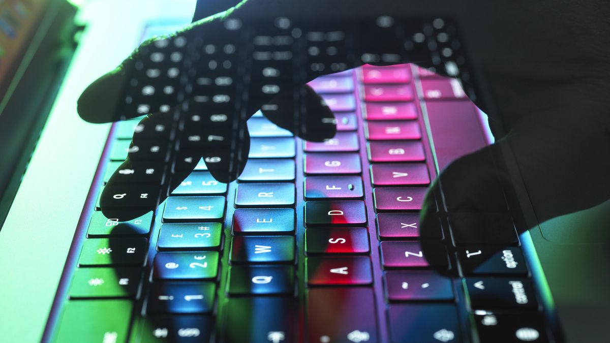 A translucent hand in shadow typing on a colourful keyboard