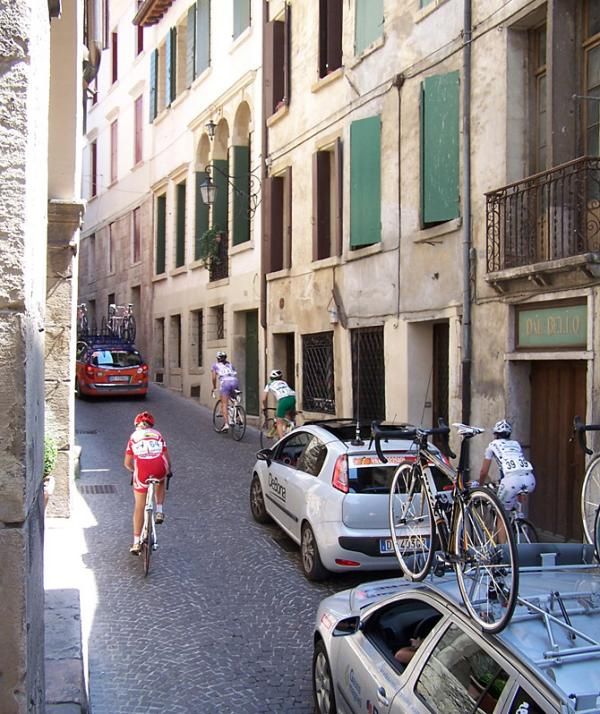 The stragglers make their way among the team cars on the cobbled climb.