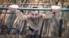 Man hanging from outdoor pull-up bar seen from above