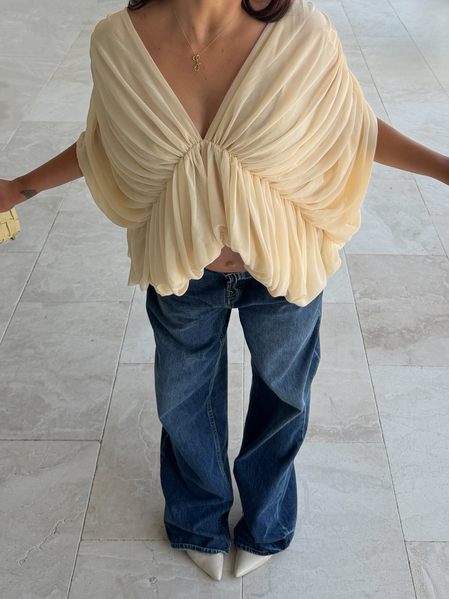 An image of a woman wearing a blouse and jeans summer outfit 2026