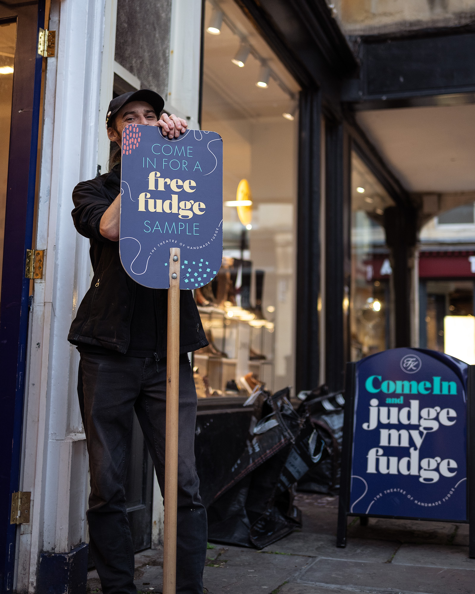 Street photograph of man holding 'free fudge' sign