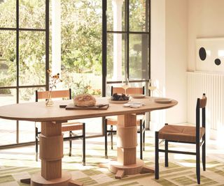 dining area with woden oval table and rush woven chair and crittal doors and geometric rug