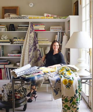 Schumacher's creative director, Dara Caponigro sitting at desk, surrounded by fabrics and books