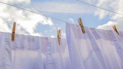 White shierts hanging on a line to dry under a blue sky