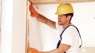 Man wearing yellow safety hat hanging wallpaper