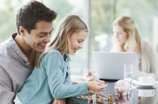 Girl counting money on table with Mum and Dad