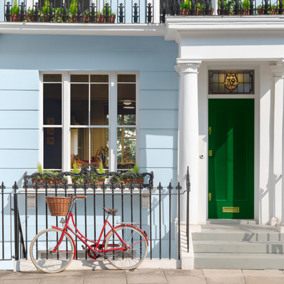 Front of windsor garden home. Blue walls and green door with red bike parked at the front