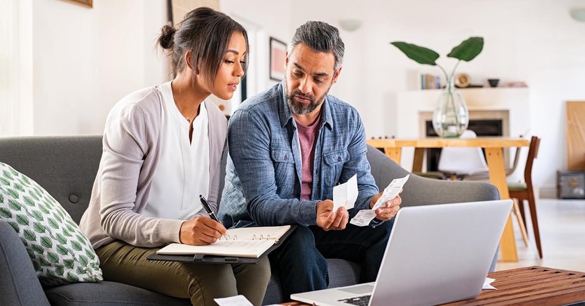 Latin straight couple sitting on couch reviewing their finances