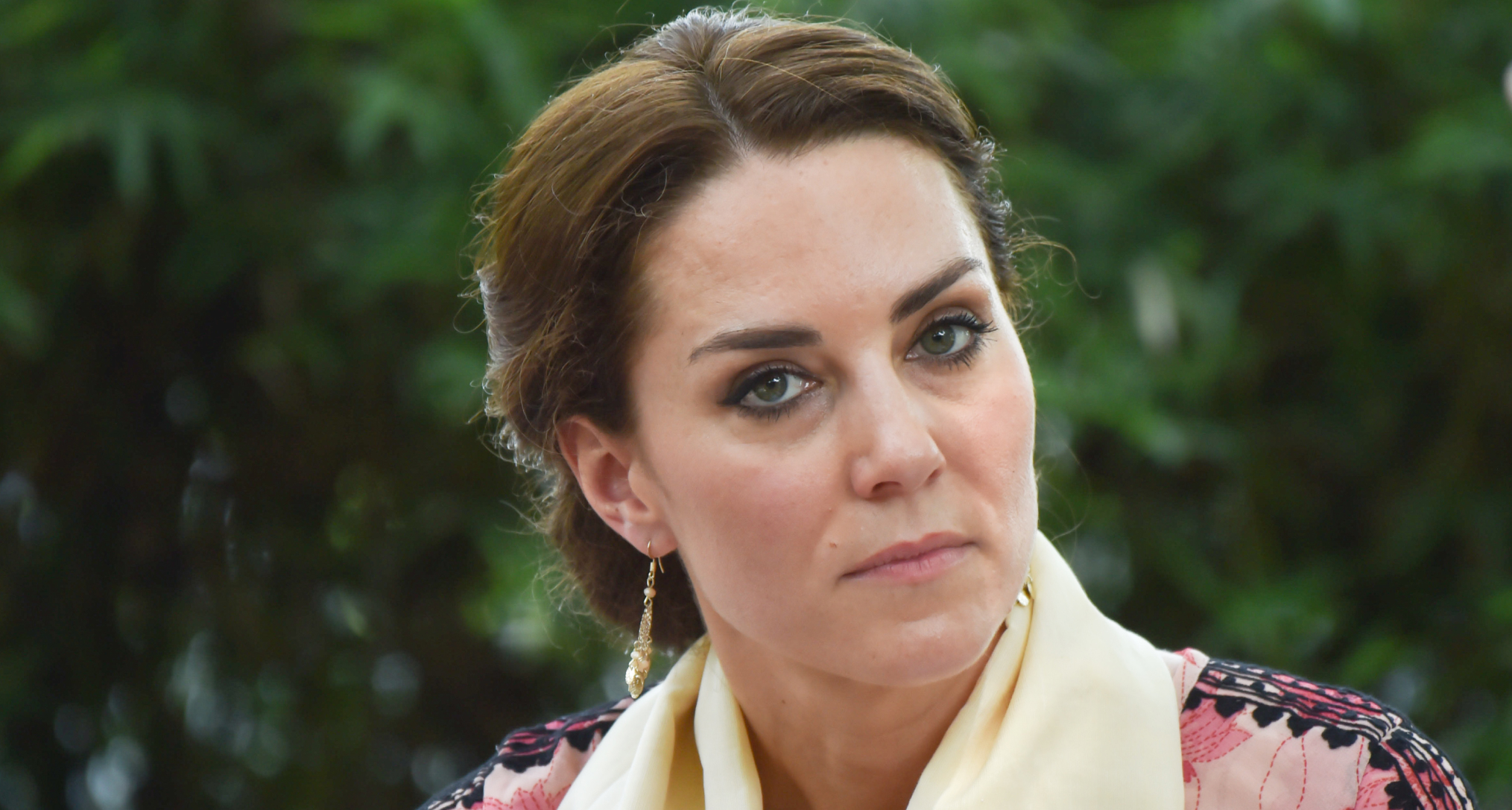 A headshot of Princess Kate wearing a yellow scarf around her neck and pink patterned dress