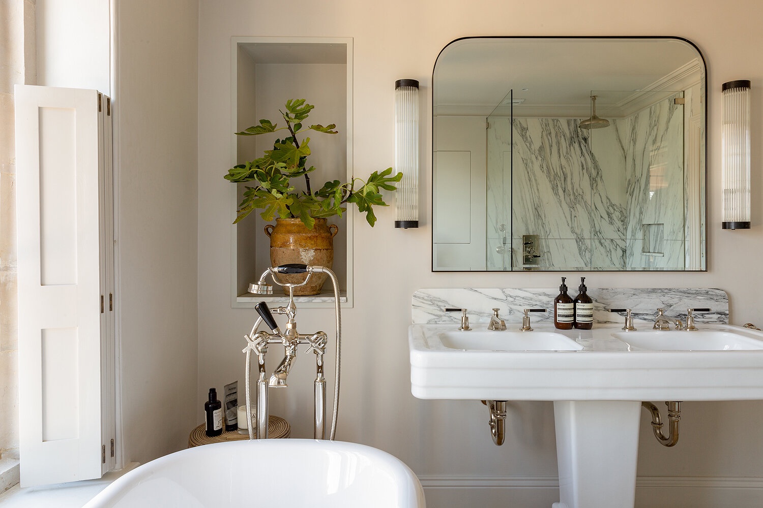 A soft pink bathroom with wall lighting