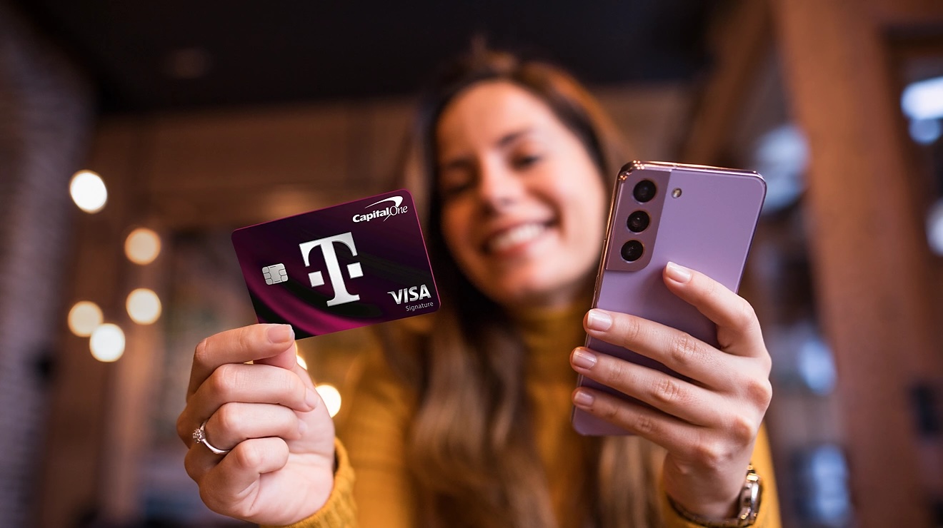 A woman holding her T-Mobile phone and Visa credit card.