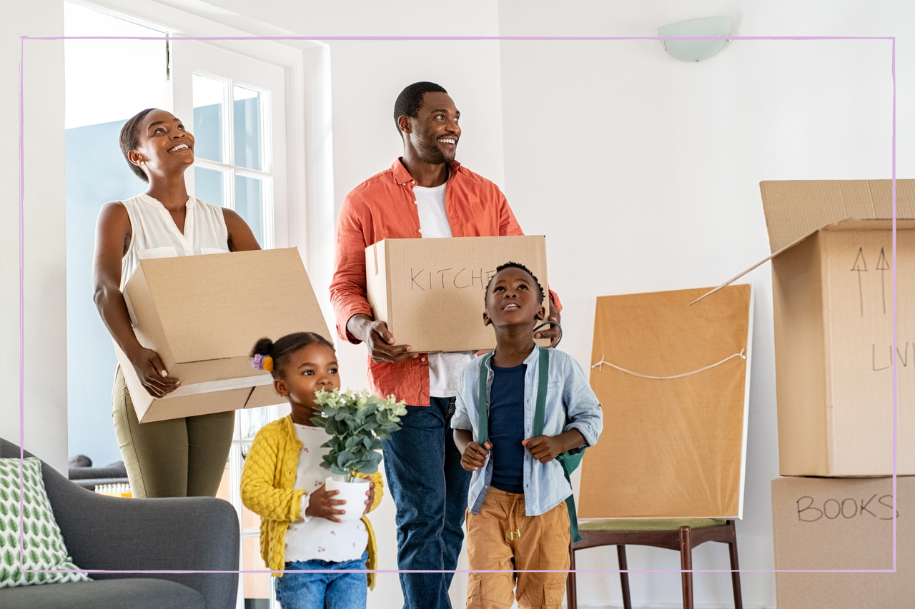 Beautiful african american family with two children carrying boxes in a new home