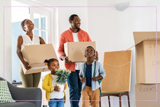 Black family with two children holding boxes ready to move into their new house