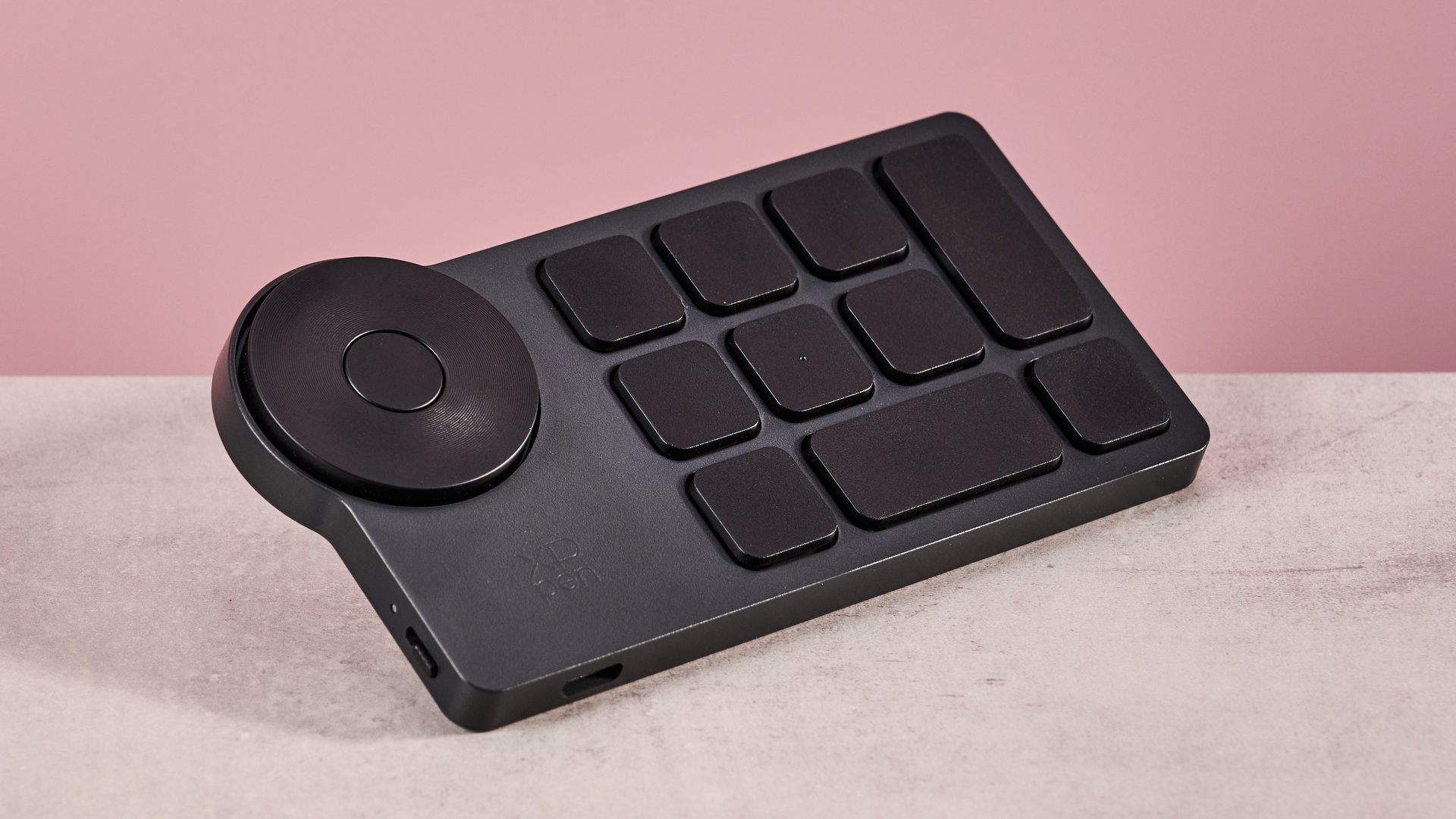 A closeup of the XPPen Artist Pro 19 Gen 2's shortcut remote in front of a pink background.