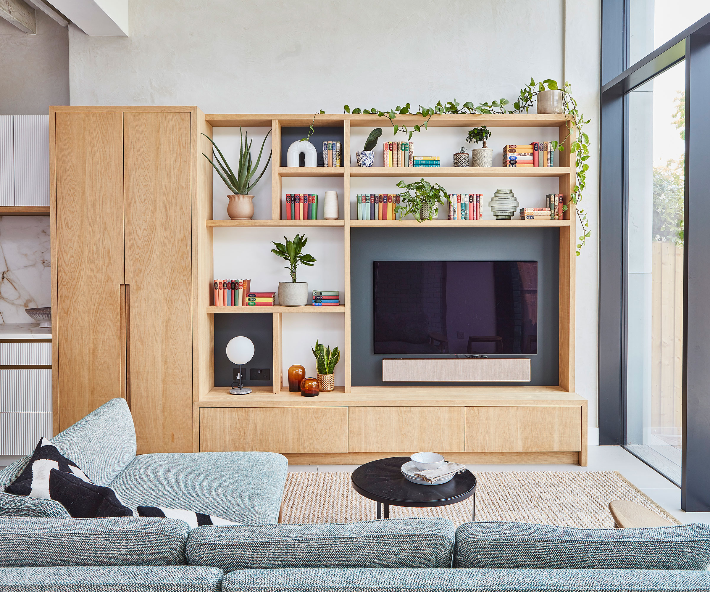 modern living room with media wall and built in storage with grey L-shaped sofa