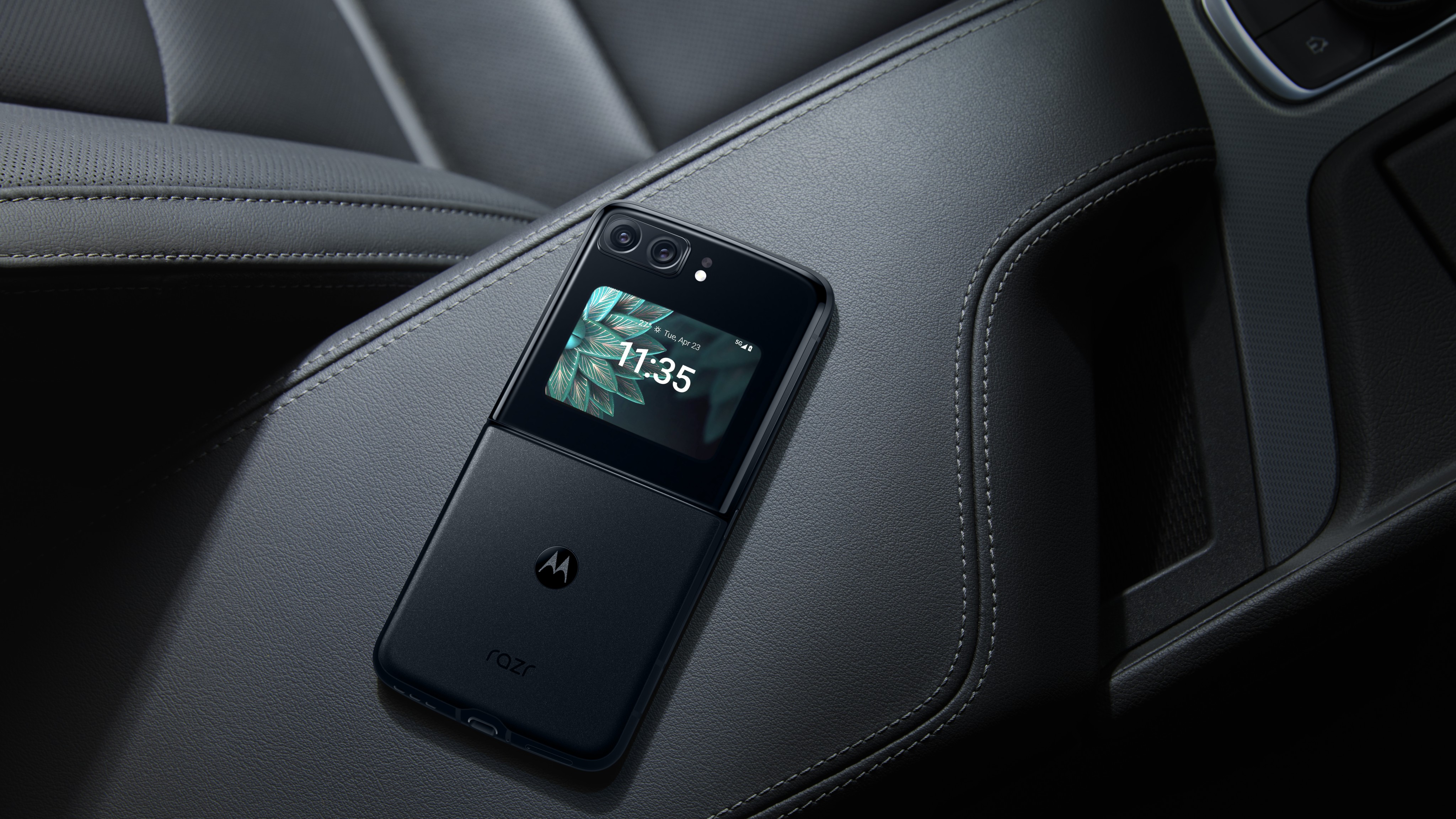 Motorola RAZR 2022 ligger med bagsiden opad på et læderklædt armlæn i en dyr bil.