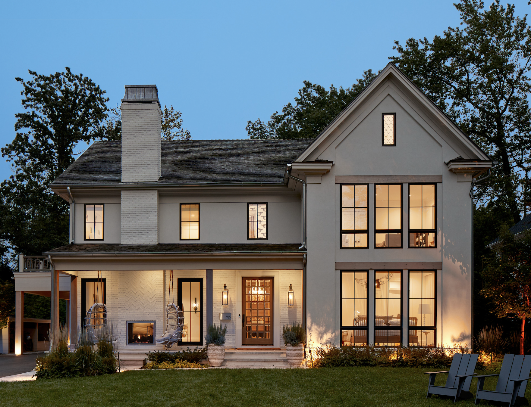 A well lit home with sconces either side of the front door and porch swings