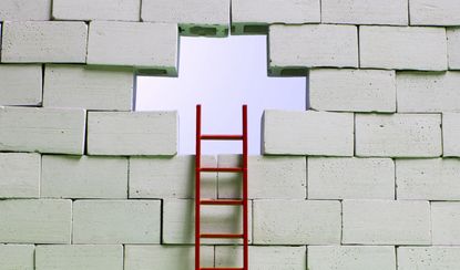 A red ladder leans against a hole in a block wall.