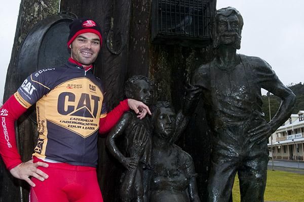 Tour leader Rhys Pollock (Drapac Porsche) poses with a statue of a Queenstown mining family.