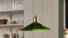 Anthropologie green glass pendant light painted with botanical motifs hanging inside of a charming white breakfast nook