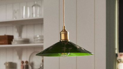 Anthropologie green glass pendant light painted with botanical motifs hanging inside of a charming white breakfast nook