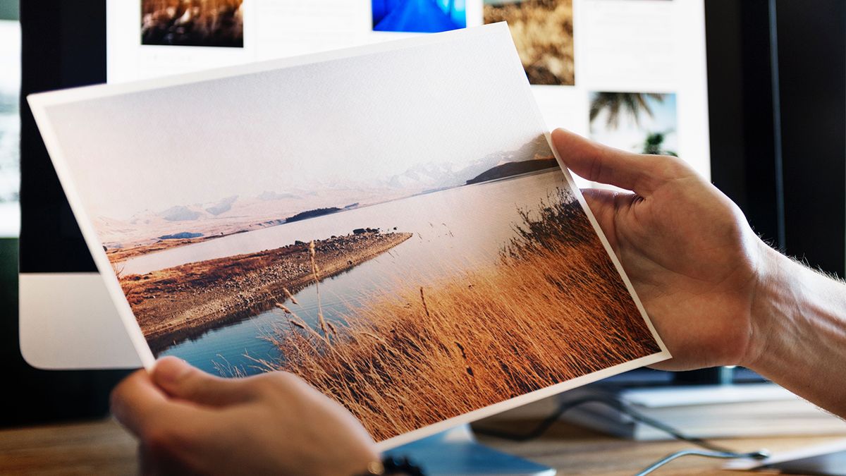 Hands holding a photo of a lake