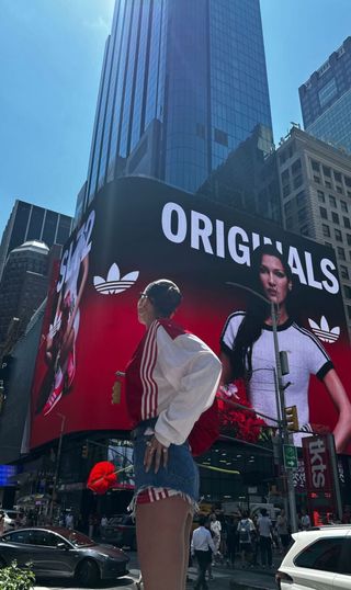 Bella Hadid in Times Square wearing cut off denim shorts and a soccer jersey from Adidas